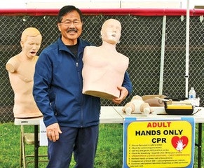 A man demonstrates CPR techniques with training mannequins at an educational booth.