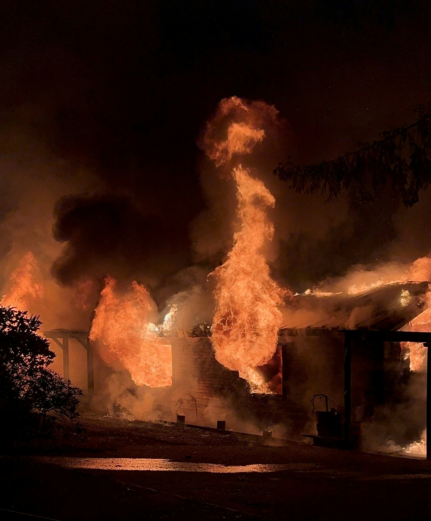 A building engulfed in flames against a dark sky, with intense fire emanating from windows and roof.