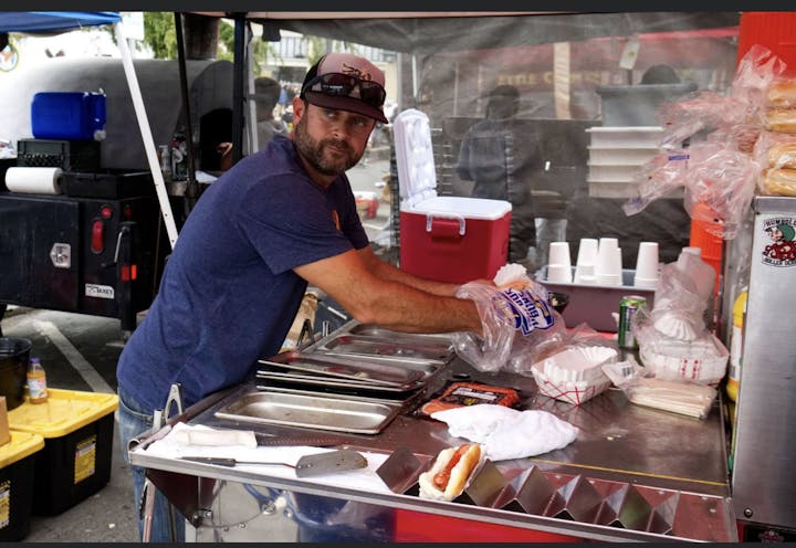 Person cooking in an outdoor food booth.