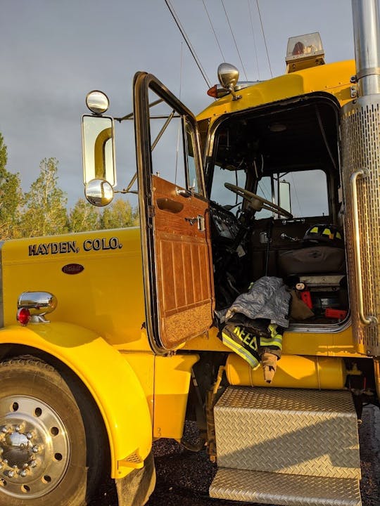 Open door of a yellow fire truck with gear and equipment visible inside.
