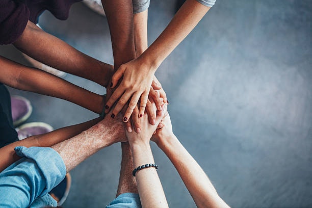 A group of people stacking hands together in a gesture of teamwork and unity.