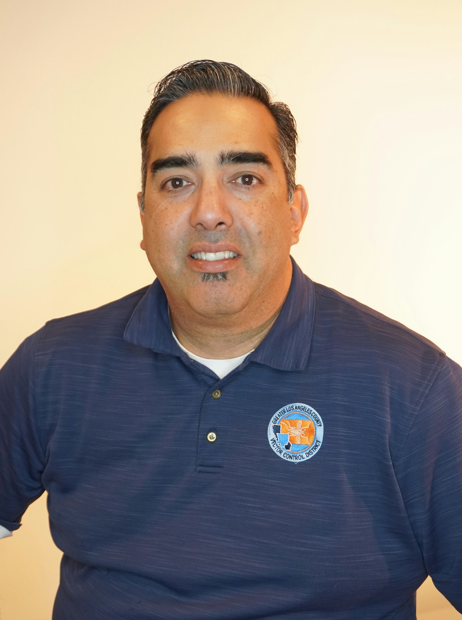 A person in a blue polo shirt with an embroidered logo on the chest.