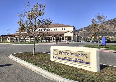 Don Vleyra Community Park entrance sign with a building and trees in the background.