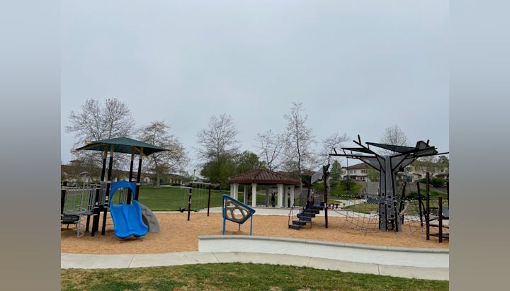 Playground with slides, climbing structures, and a gazebo on a cloudy day.