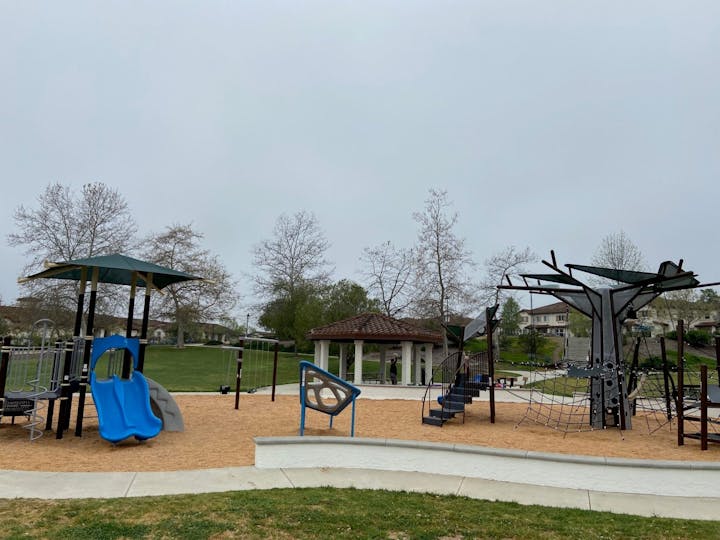 Playground with slides, climbing structures, and a gazebo on a cloudy day.