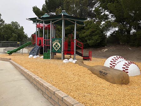 Children's playground with slides, a mini climbing wall, and a theme resembling a baseball field.