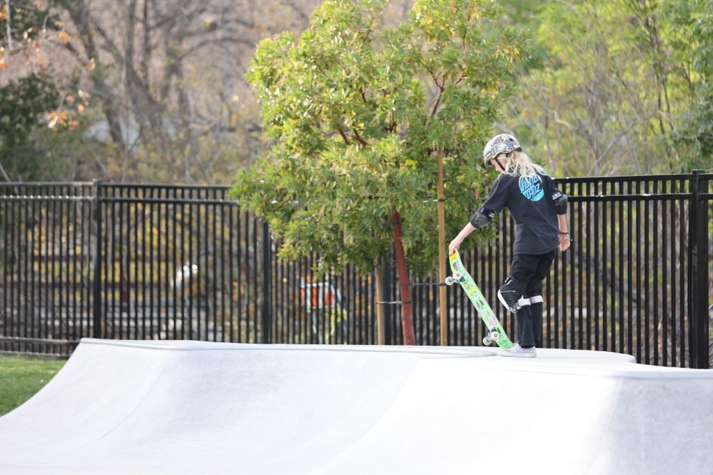 A person with a helmet is preparing to skateboard on a ramp in a park.