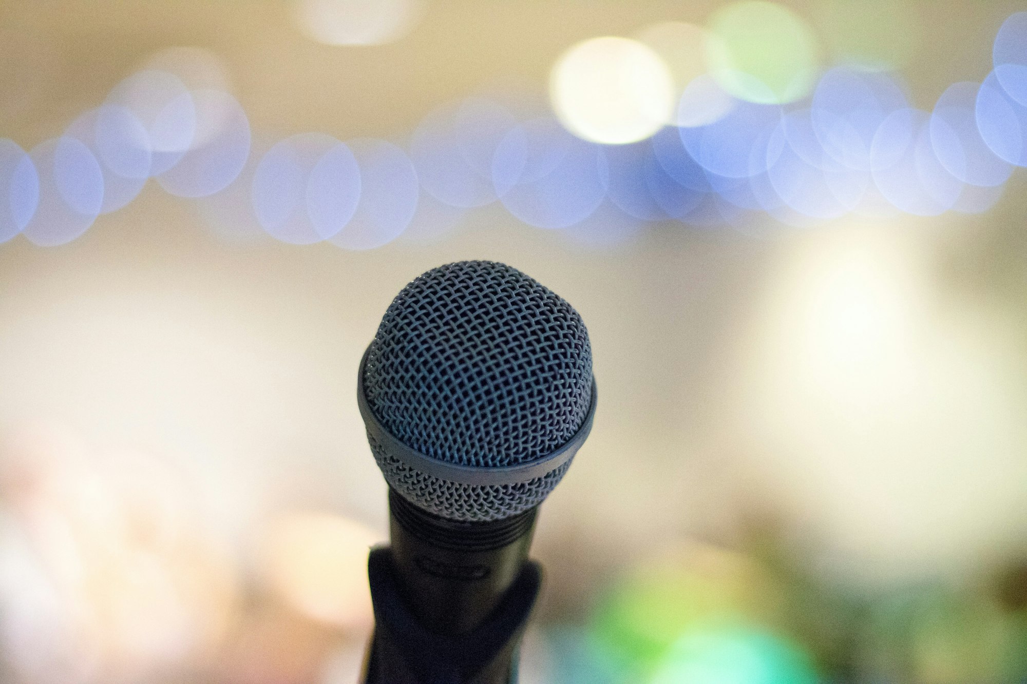 A microphone in focus against a blurred background with blue and white bokeh lights.