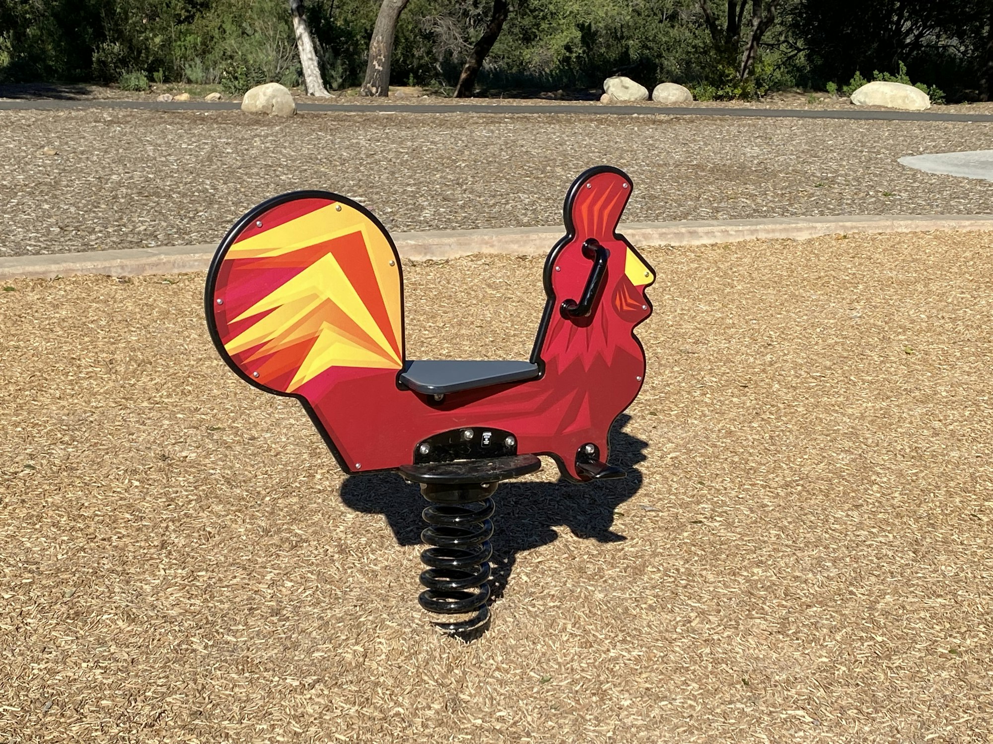 A playground spring rider shaped like a red squirrel with a colorful tail.