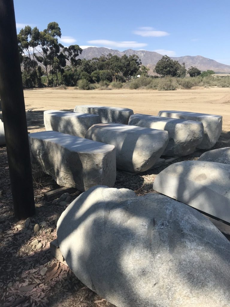 Large gray rocks in a dirt clearing with trees and mountains in the background.