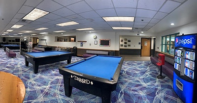 Game room with pool tables, Pepsi vending machine, and seating area.