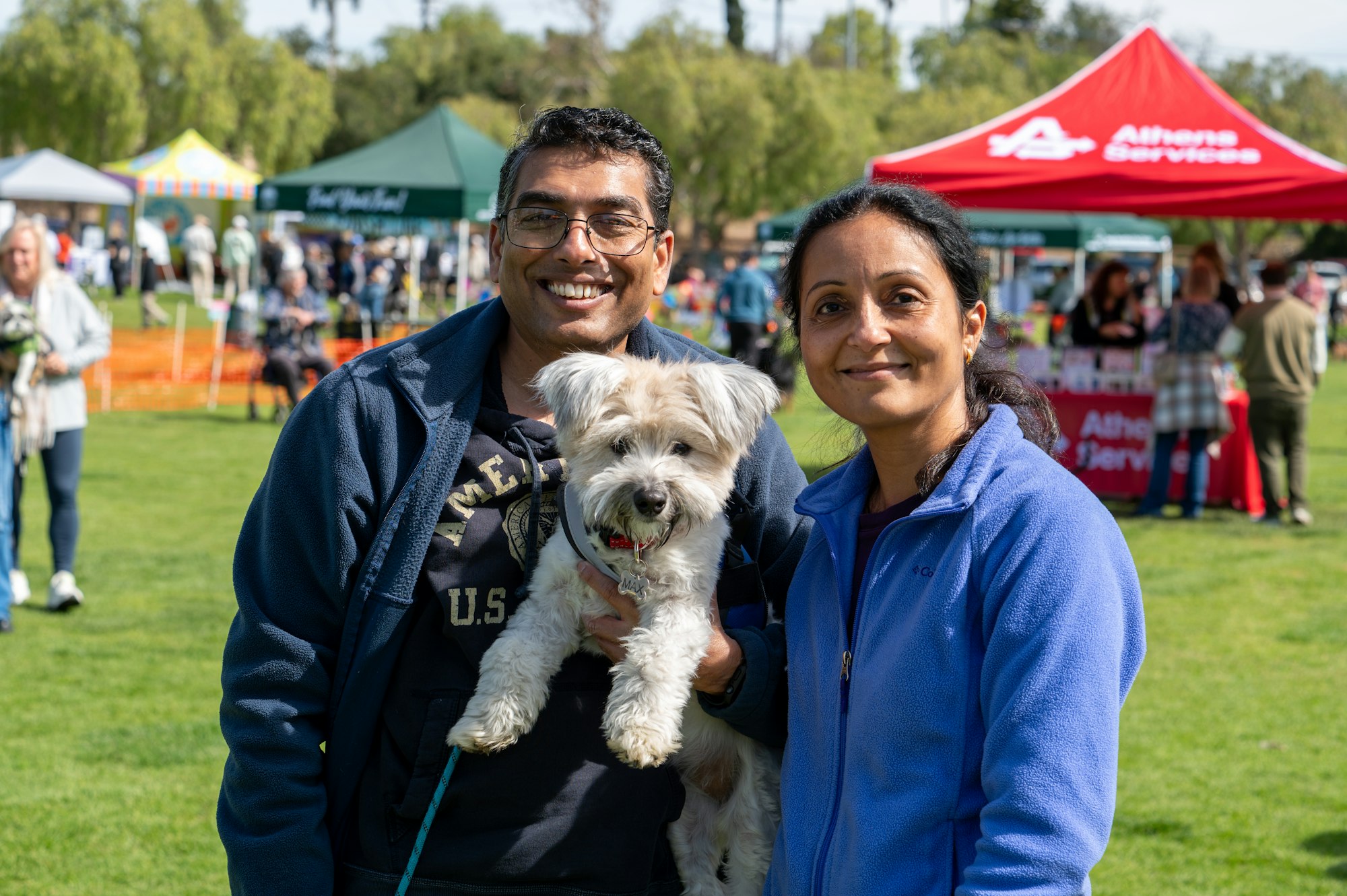 May contain: grass, plant, adult, male, man, person, accessories, glasses, female, woman, clothing, footwear, shoe, tent, nature, outdoors, park, people, animal, canine, dog, mammal, pet, and terrier