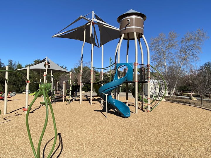 Playground with slides, climbing structures, and shade canopies on a sunny day.