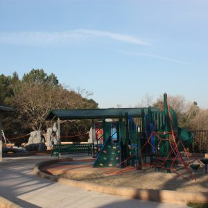 Playground with slides, climbing structures, and trees in the background.