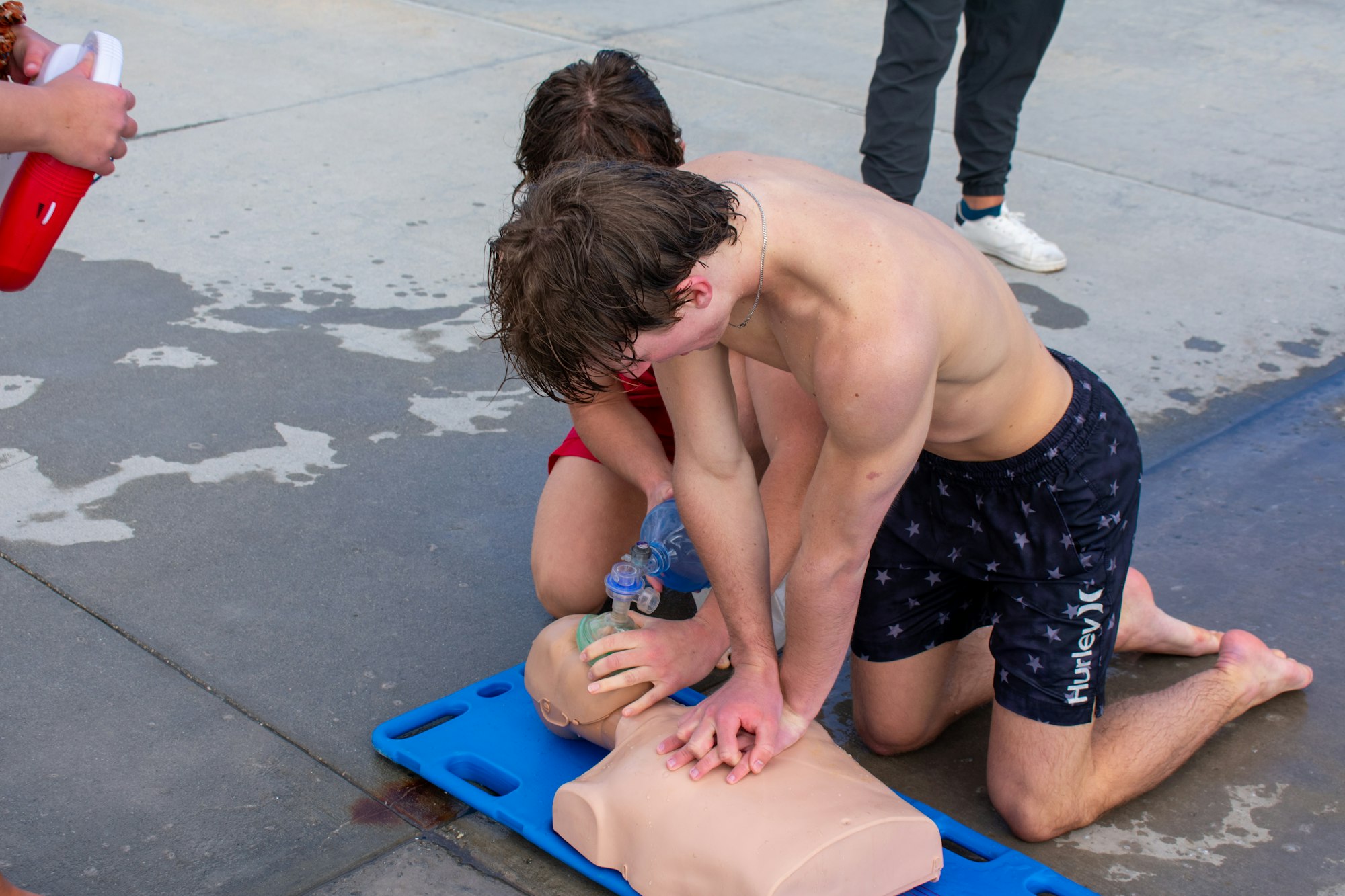 People practicing CPR on a dummy outdoors.