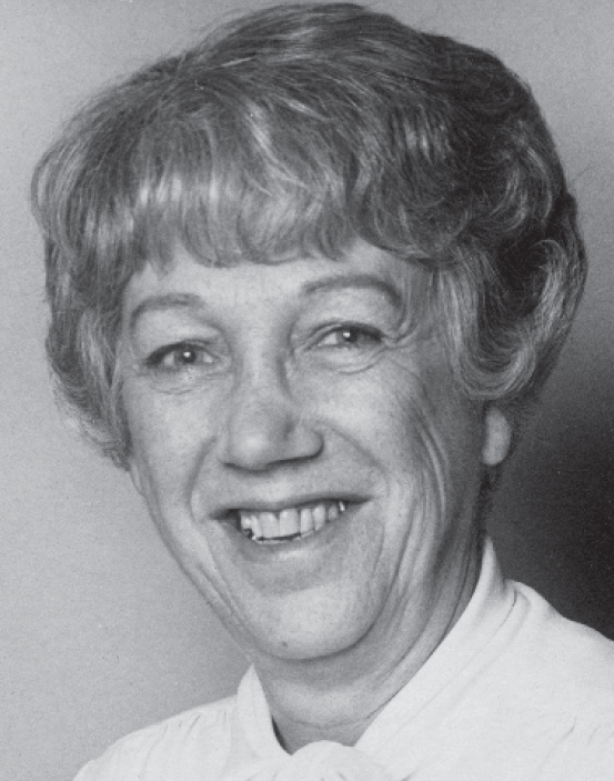 Portrait of a smiling older woman with short hair and a white shirt.