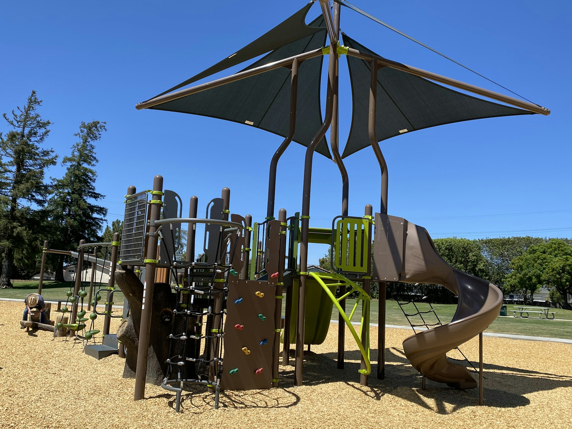 Children's playground with climbing structures and a slide in a park setting.