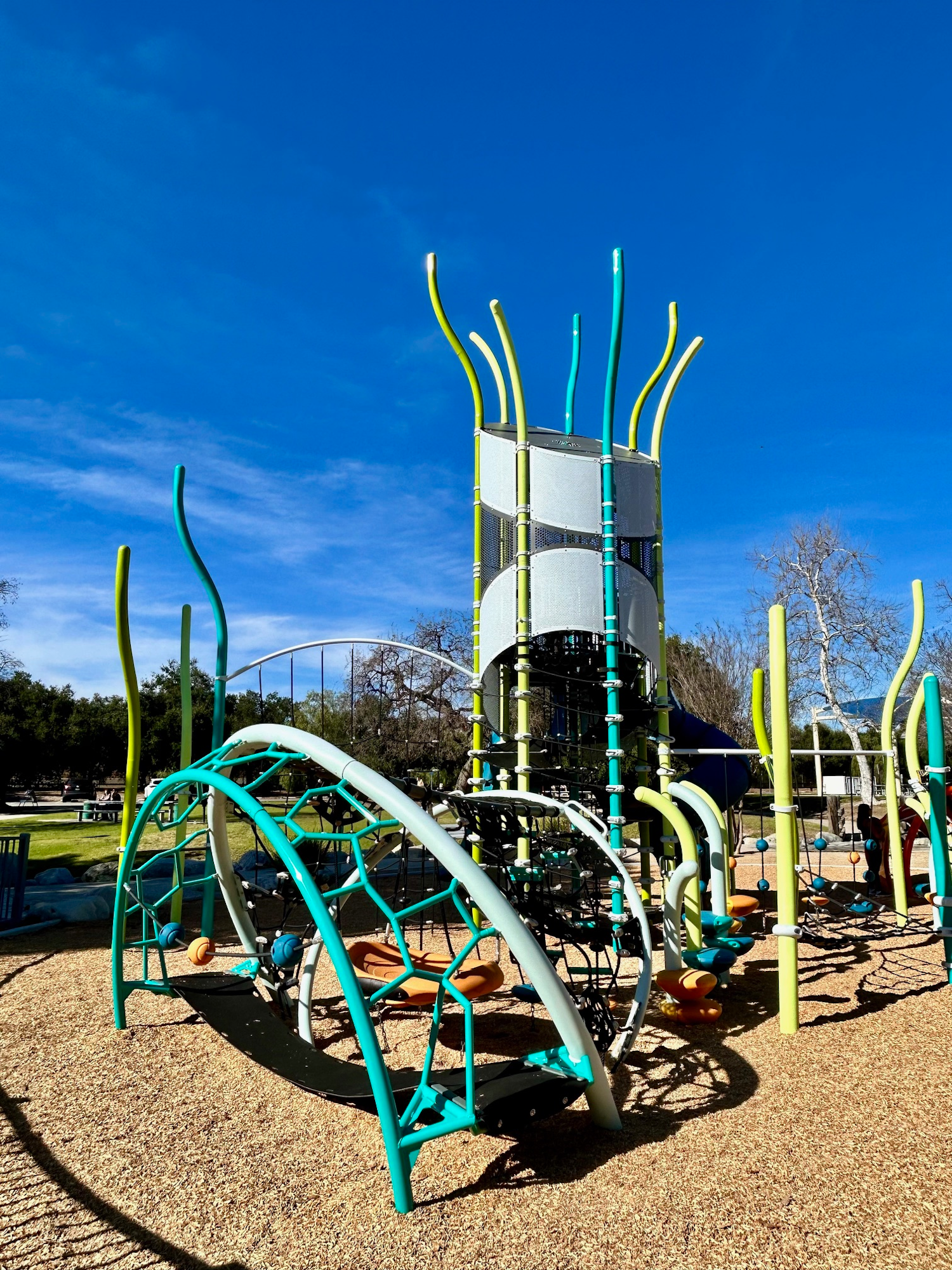 Playground with colorful climbing structures and slides under a clear blue sky.