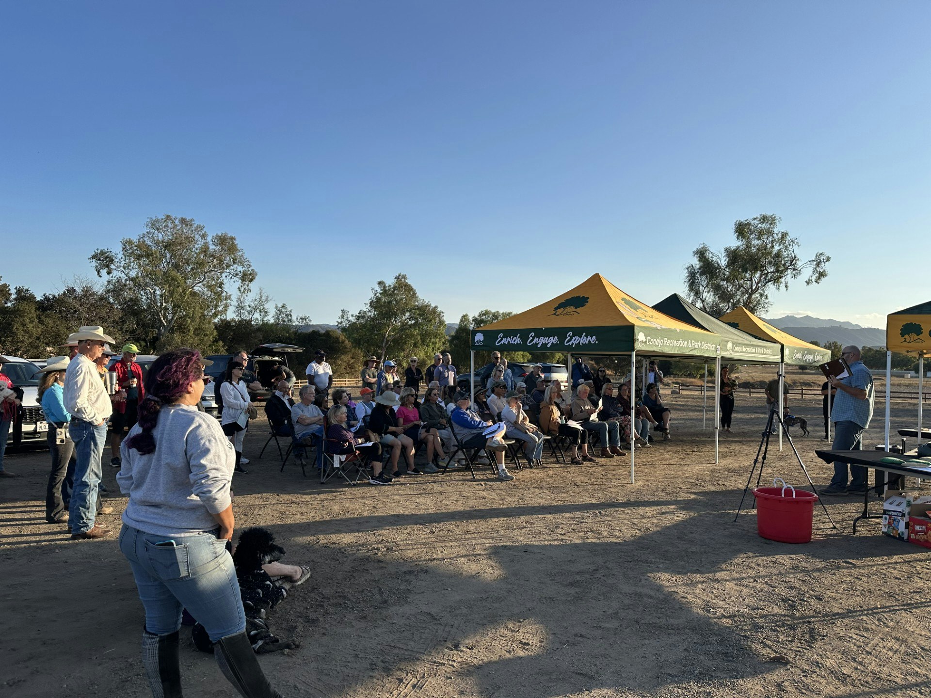 A group of people are gathered under tents labeled "Conejo Recreation & Park District" for an outdoor event or meeting.