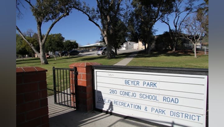 Sign for Beyer Park at 280 Conejo School Road, surrounded by trees and a parking area.
