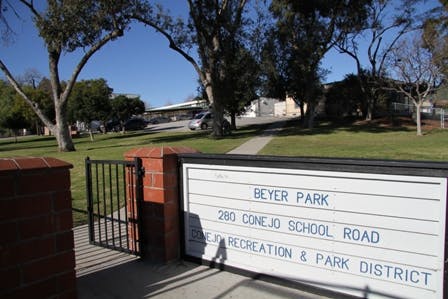 Sign for Beyer Park at 280 Conejo School Road, surrounded by trees and a parking area.