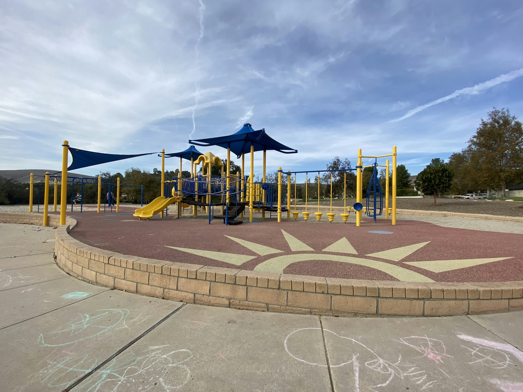 Playground with slides and climbing structures, surrounded by drawings on the concrete.