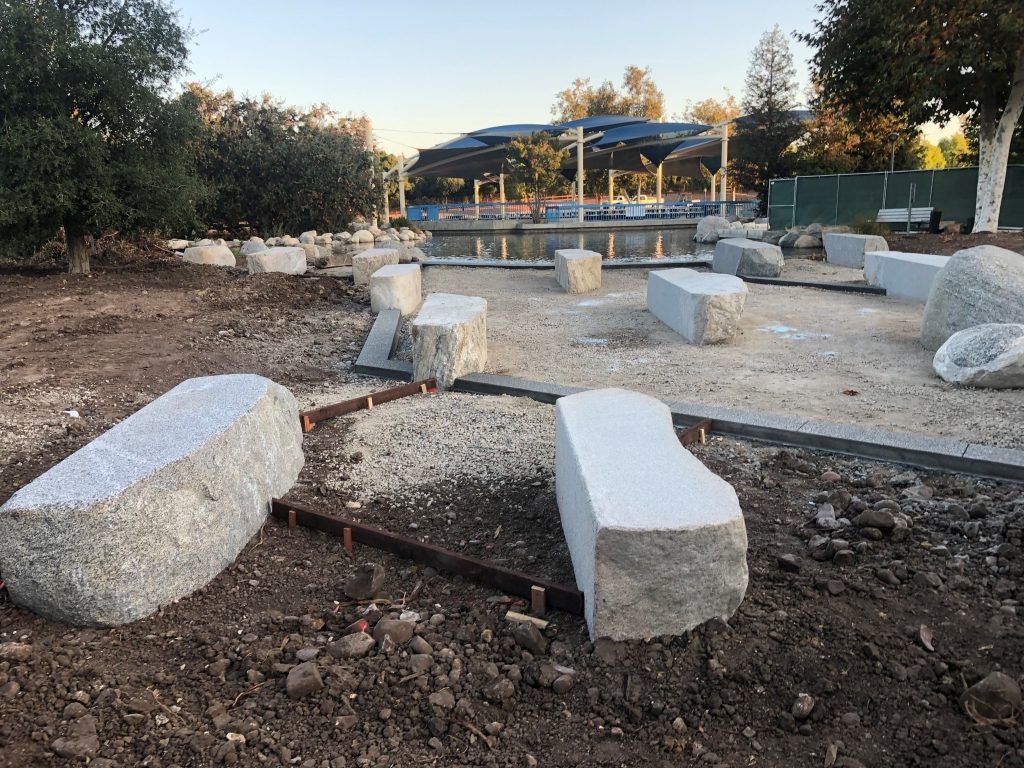 Rocks and gravel set in a partially cleared outdoor area with trees and a covered seating area in the background.