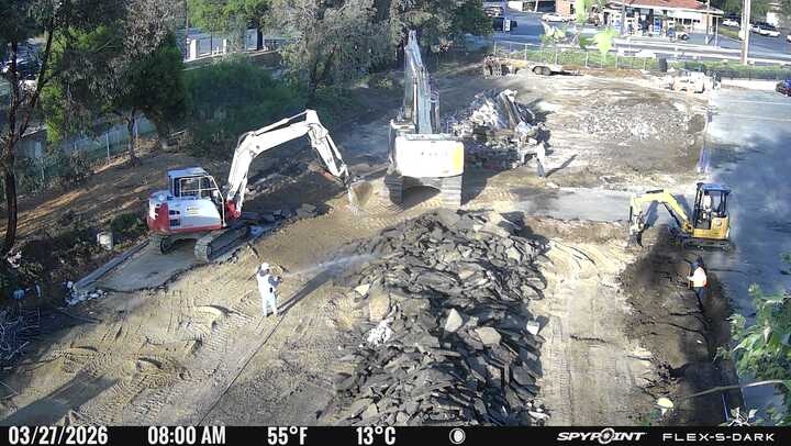 Construction site with heavy machinery digging and moving debris, likely preparing land for a new project.
