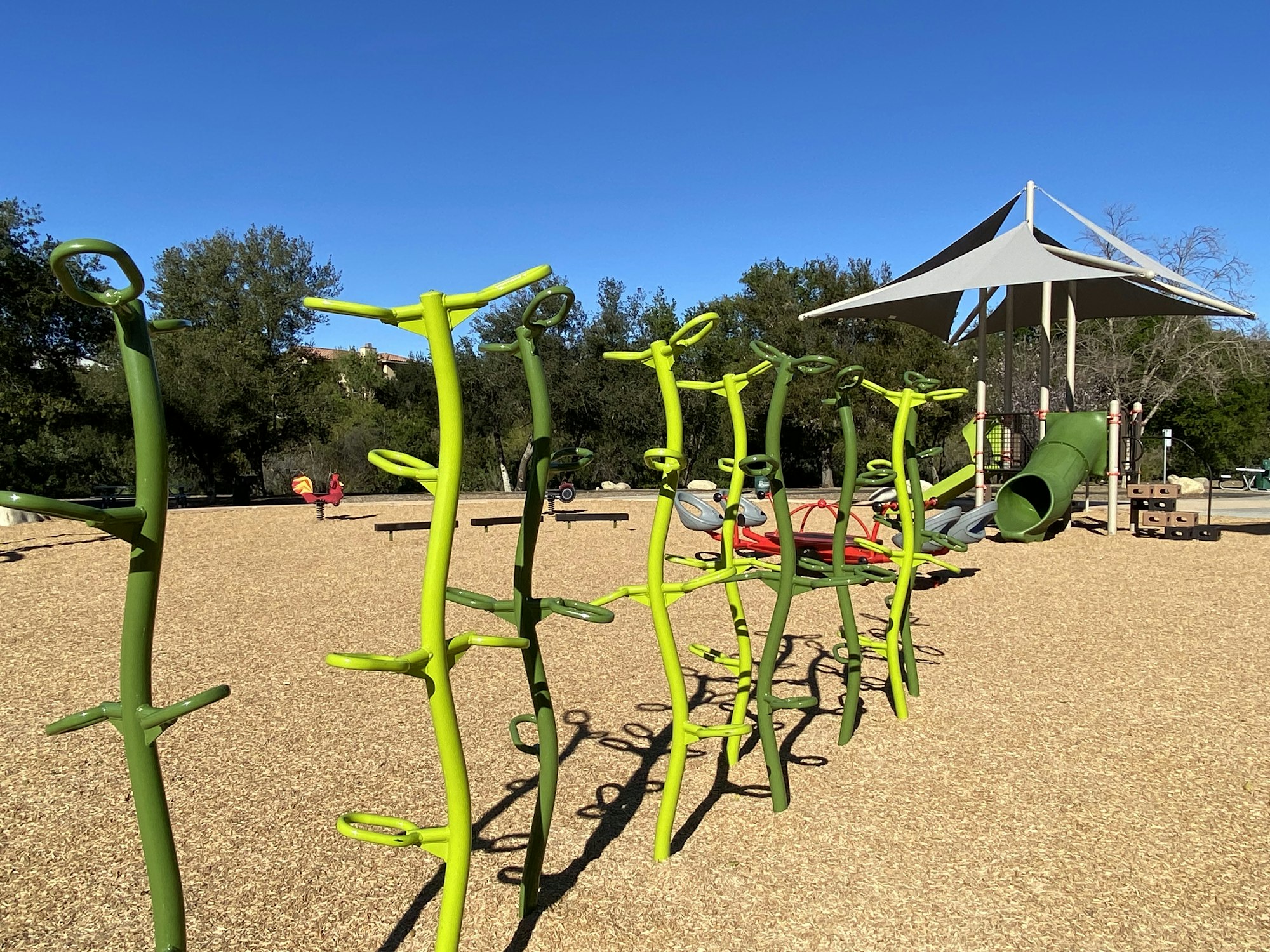 Playground with climbing structures, slide, and a canopy on a clear day.