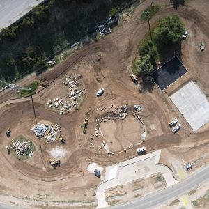 Aerial view of a construction site with vehicles, dirt roads, and piles of materials.