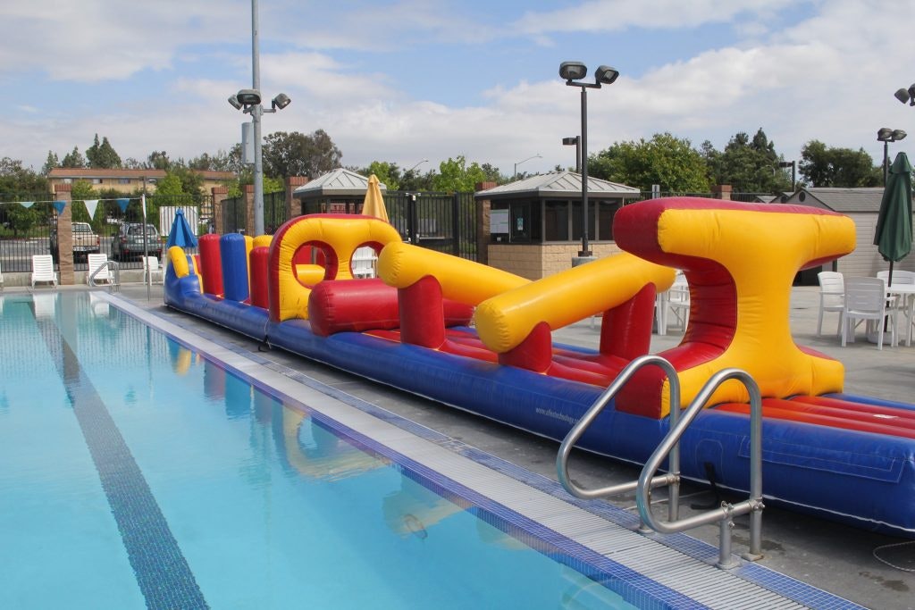 Inflatable obstacle course set up alongside a swimming pool.