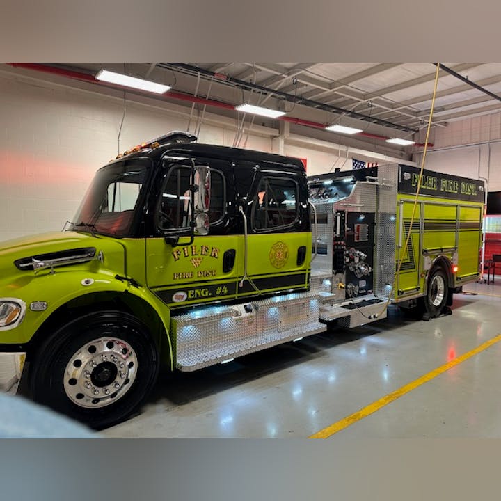 Green fire truck labeled "Filer Fire Dist. Eng. #4" parked indoors in a garage.