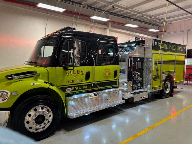 Green fire truck labeled "Filer Fire Dist. Eng. #4" parked indoors in a garage.