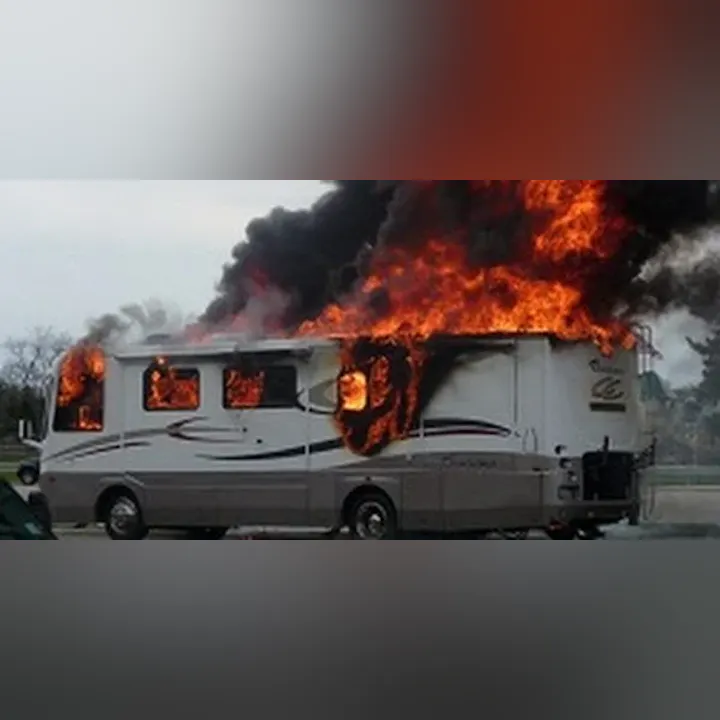 A motorhome engulfed in flames with thick black smoke rising.
