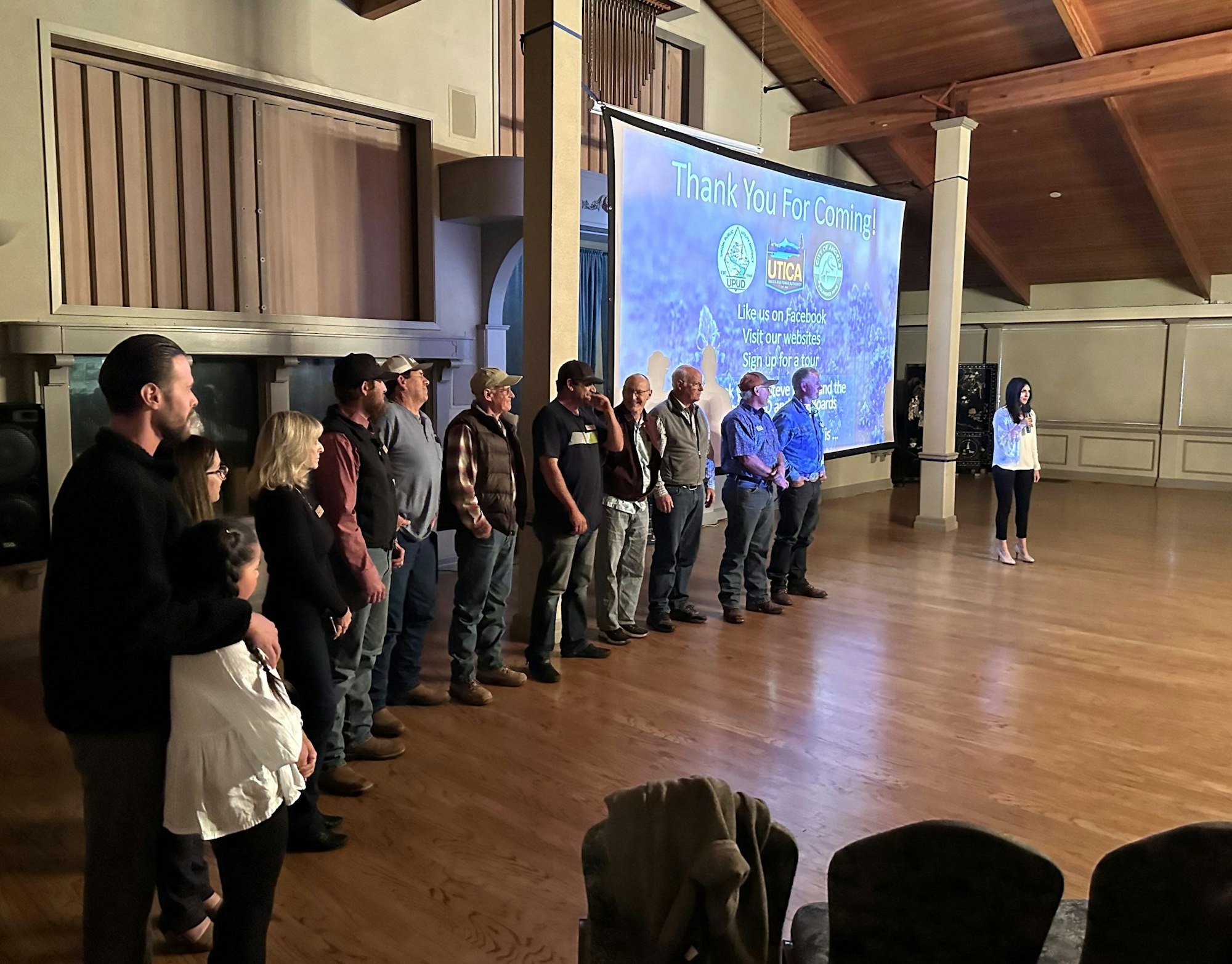 A group of people standing in line on stage, facing a projection screen that says "Thank You For Coming!"