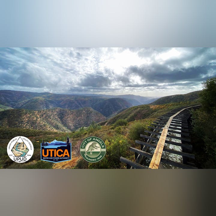 Mountain landscape with cloudy sky, a wooden aqueduct, and logos of UPUD, UTICA, and the City of Angels in the foreground.