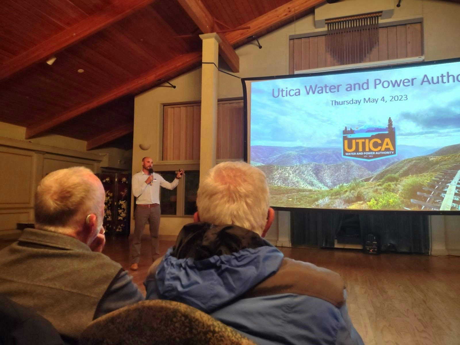 A presenter speaks to an audience with a slideshow titled "Utica Water and Power Authority," dated May 4, 2023.