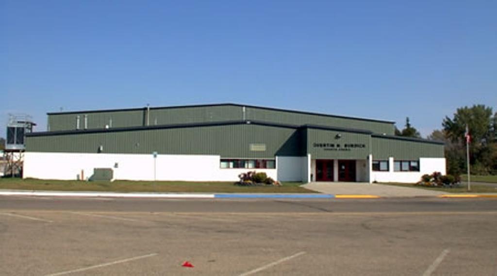Industrial building with a sign, clear sky, and parking area.