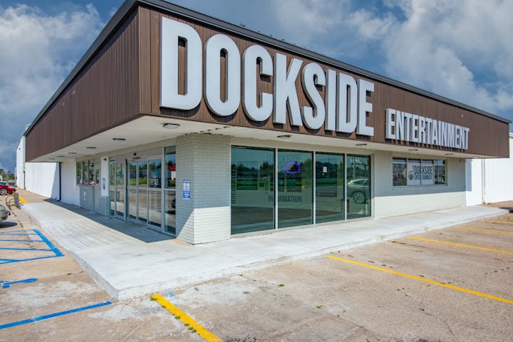 A building with "Dockside Entertainment" signage, featuring large glass windows and accessible entry, in a parking lot.