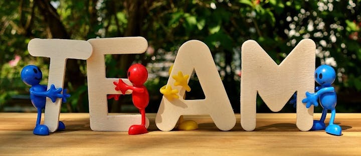 Colorful figures with the word "TEAM" in large letters, evoking teamwork and collaboration.
