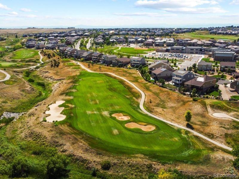 Aerial view of a golf course with sand bunkers alongside a residential area.