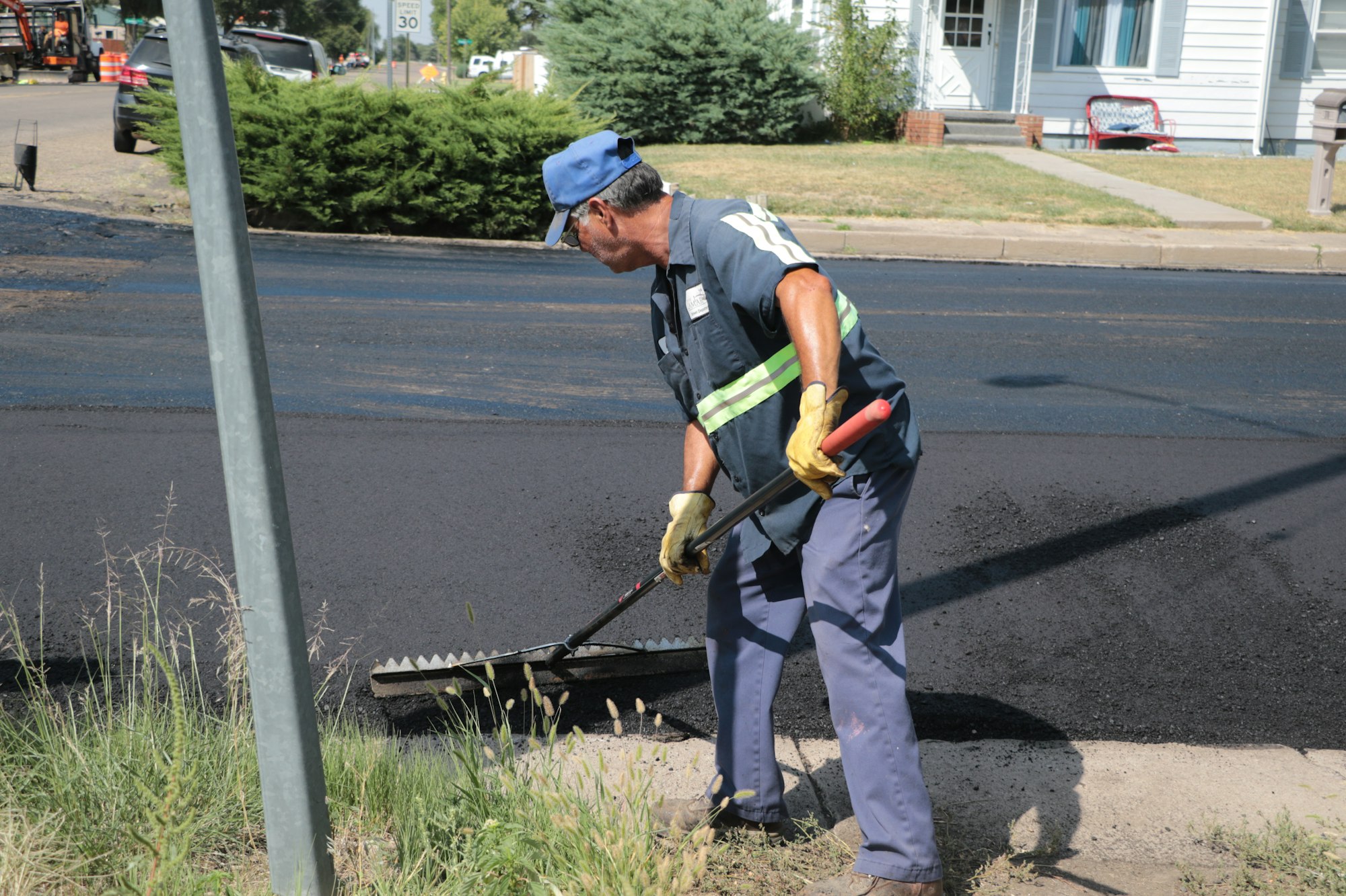 A worker spreading asphalt for road resurfacing.