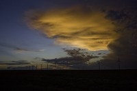 A dramatic cloudy sky at sunset, with a silhouette of power lines along the horizon.