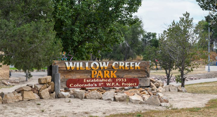 Sign for Willow Creek Park, established 1933, Colorado's 1st W.P.A. Project, surrounded by rocks and trees.