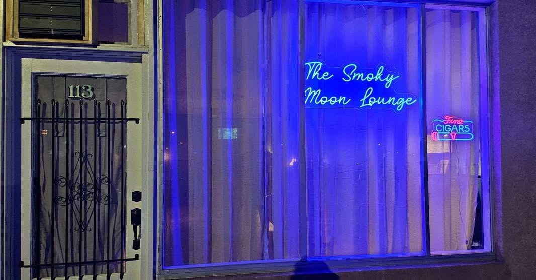 A neon sign for "The Smoky Moon Lounge" and "Fine Cigars" with a door numbered 113.