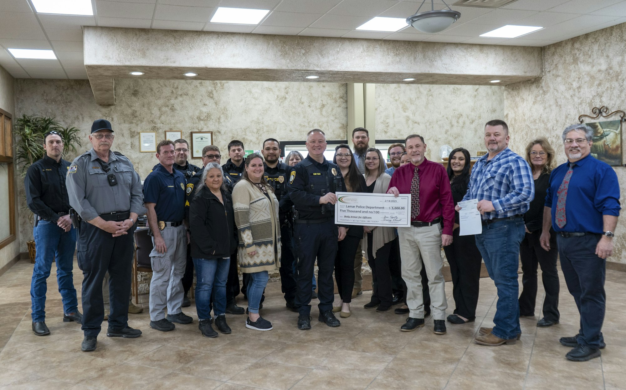 A group of people indoors, with some holding a large check for $5,000 made out to the Lamar Police Department.