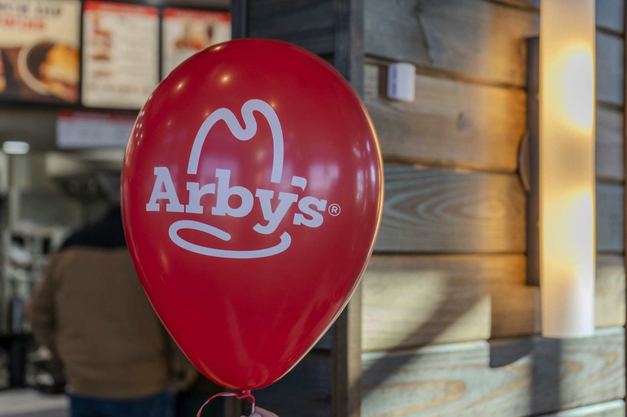 Red Arby's balloon inside a restaurant with blurred background.