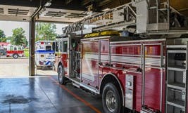 A fire truck and an ambulance parked in a garage, ready for emergency response.