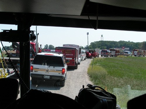 A line of emergency vehicles, including fire and rescue trucks, on a rural road, likely responding to an incident.