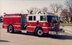 A red fire truck parked on a road near some buildings.